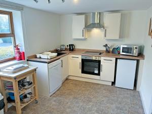 a kitchen with white cabinets and a stove top oven at Rose Cottage - Uk51373 in Winston