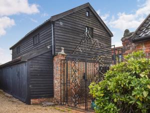 a black house with a gate in front of it at Cartlodge Loft in Roydon