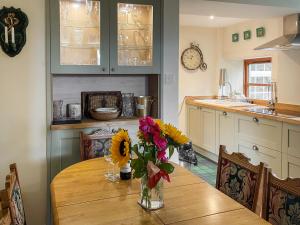 a kitchen with a table with a vase of flowers on it at Aldersyde in Tighnabruaich