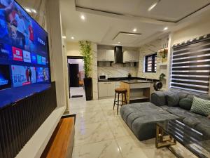 a living room with a couch and a large screen tv at Less2More Luxury Suites in Agege