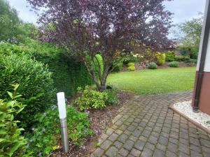 a garden with a tree and a brick walkway at Ferienhaus Am Sonnenhang in Zerf +31 photos