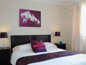 a bedroom with a bed with a purple painting on the wall at Carnethy in Tighnabruaich +5 photos