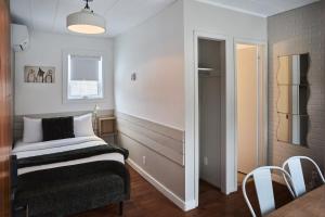 a small room with a bed and a refrigerator at Motel Boutique Hygge - anciennement Aux Portes du Soleil in Baie-Saint-Paul