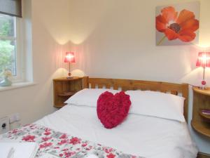 a red heart pillow on a bed in a bedroom at Ysgubor Uchaf - 29517 in Fairbourne +14 photos