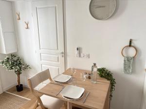 a dining room with a table and a clock on the wall at Le Japandi Maison confortable et calme à Libourne in Libourne