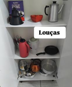 two shelves filled with pots and pans at Ap do Edney Águas de Lindoia in Águas de Lindoia