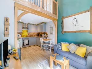 a living room with a blue couch and a kitchen at Coachmans Cottage - Uk50418 in Bisterne