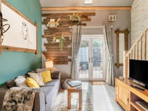 a living room with a couch and a tv at Coachmans Cottage - Uk50418 in Bisterne