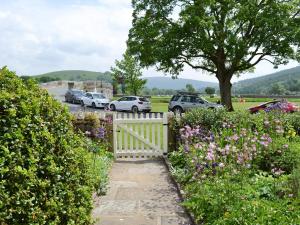 a white fence with flowers and cars parked in a parking lot at Clematis Cottage in Burnsall