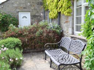 a bench sitting in front of a house at Clematis Cottage in Burnsall