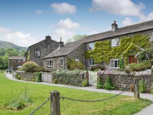 an old stone house with ivy growing on it at Clematis Cottage in Burnsall