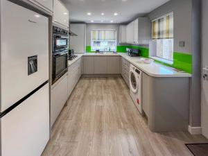 a kitchen with white cabinets and green accents at Newington House in Ramsgate