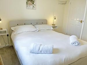 a white bed with two towels on top of it at Ivy Cottage - Uk51372 in Winston