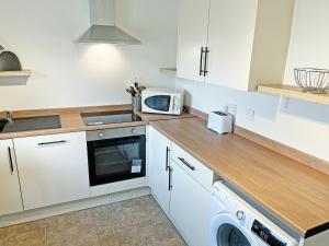 a kitchen with white cabinets and a microwave at Ivy Cottage - Uk51372 in Winston