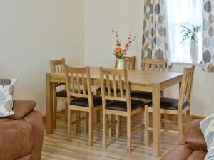 a dining room with a wooden table and chairs at Hen Ysgubor - 29518 in Fairbourne +7 photos