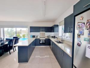 a kitchen with blue cabinets and a dining room at luxury villa utopia 2 in Paphos