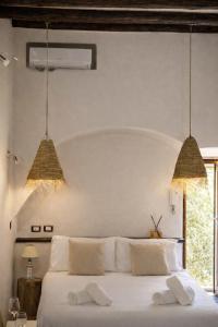 a bedroom with a white bed with two hanging lights at Spinuzza Boutique Guesthouse Cefalù, Sicily in Cefalù