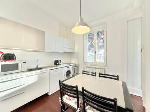 a kitchen with white cabinets and a table and chairs at VILLA MARE BLU in Levanto