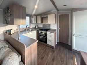 a kitchen with a stove top oven next to a couch at Simon's Coastal Holiday Home in Ormesby Saint Margaret