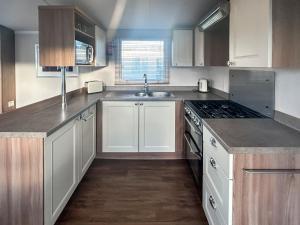 a kitchen with white cabinets and a stove top oven at Simon's Coastal Holiday Home in Ormesby Saint Margaret