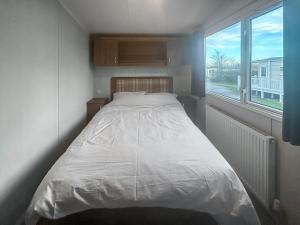 a small bedroom with a bed and a window at Simon's Coastal Holiday Home in Ormesby Saint Margaret