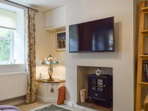 a living room with a fireplace with a television on a wall at Spire View Cottage in Olney