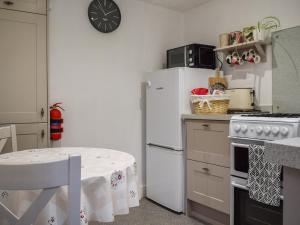 a kitchen with a white refrigerator and a table at Spire View Cottage in Olney