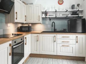 a kitchen with white cabinets and a black microwave at Redgauntlet in Skinburness