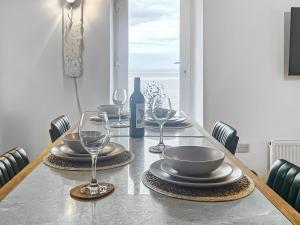 a table with glasses and plates and a bottle of wine at Redgauntlet in Skinburness +20 photos