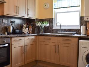 a kitchen with wooden cabinets and a sink and a window at Elm Court 7 in Keswick