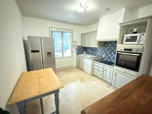 a kitchen with white appliances and a wooden table at La Laurisienne in Lauris