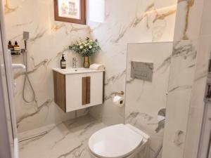 a white bathroom with a toilet and a sink at Kasibel Suites in Sandanski +1 photo