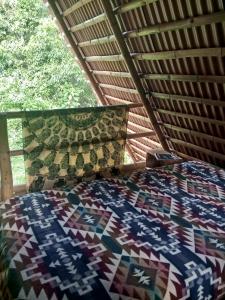 a bedroom with a bed with a quilt on it at Cabaña Bugambilla in Macas
