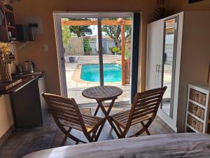 a table and two chairs in a kitchen with a pool at Fynbos & Pinot Guest Cottage in Kuilsrivier