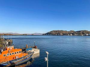 an orange boat is docked in the water at Airds Apartment in Oban