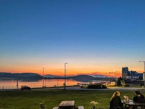 two people sitting at tables watching the sunset at Airds Apartment in Oban +18 photos