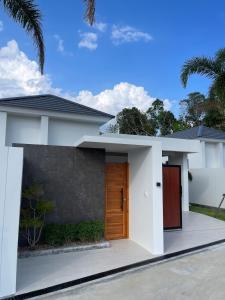 a white house with a wooden door at Vela Villa Aonang in Ban Chong Phli