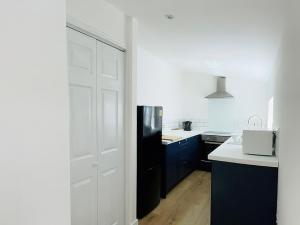 a kitchen with a white door and a black refrigerator at Ardrhu Cottage in Hunters Quay