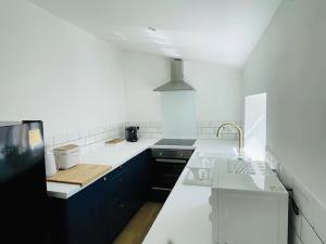 a white kitchen with black cabinets and a sink at Ardrhu Cottage in Hunters Quay +3 photos