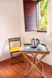 a table with a tea kettle on it next to a chair at Exclusive Guest House - Suites Charmosas na Vila in Porto De Galinhas