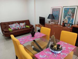 a dining room with a glass table and yellow chairs at Beach & Pool in Costa da Caparica