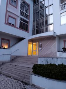 a white building with stairs and a yellow door at Beach & Pool in Costa da Caparica