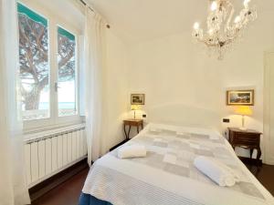 a white bedroom with a bed and a chandelier at VILLA MARE BLU in Levanto