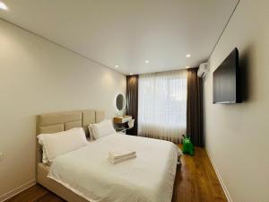a bedroom with a white bed with a flat screen tv at Apartament white in Chişinău