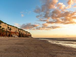 a sandy beach with a cliff in the background at Church View in Hunstanton
