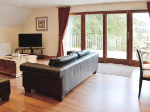 a living room with a leather couch and a television at Lime Tree Cottage in Oakley +9 photos