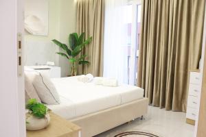 a bedroom with a white bed and a window at SSS Luxury Apartment with Jacuzzi in Kamëz