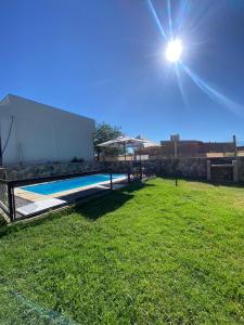 a swimming pool in a yard with the sun in the sky at Complejo Los Rosales Cafayate in Cafayate
