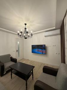 a living room with a table and a tv on the wall at Cozy Newly Renovated Apartment in Batumi Old Town in Batumi