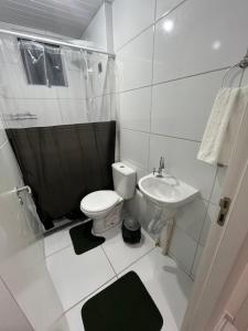 a white bathroom with a toilet and a sink at Ap à 600 metros da praia, um verdadeiro paraíso! in Barra dos Coqueiros +21 photos